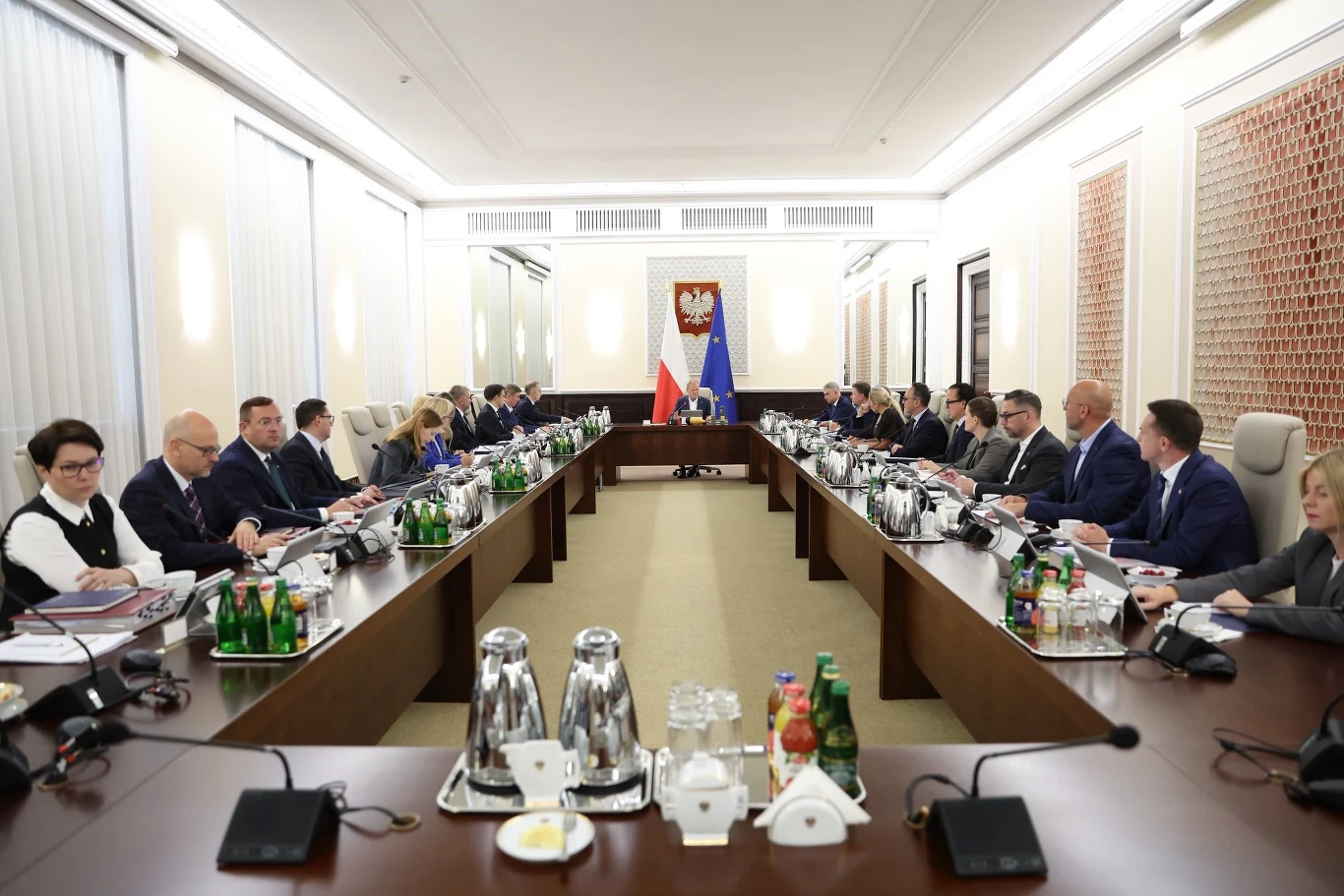 Rząd po rekonstrukcji będzie działał lepiej? Takie pytanie w sondażu zadano respondentom Duża sala konferencyjna, wokół długiego stołu siedzą politycy i urzędnicy, centralnie umieszczone flagi Polski oraz Unii Europejskiej, na ścianie godło państwowe, na stole liczne dokumenty, butelki z wodą oraz zestawy do kawy.