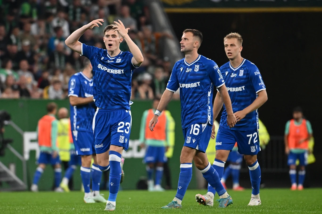 Znamy potencjalnych rywali Lecha Poznań w 4. rundzie eliminacji Ligi Mistrzów Grupa piłkarzy w niebieskich strojach drużyny Lech Poznań podczas meczu na stadionie, wyrażających emocje po jednej z akcji, w tle kibice i inni zawodnicy.