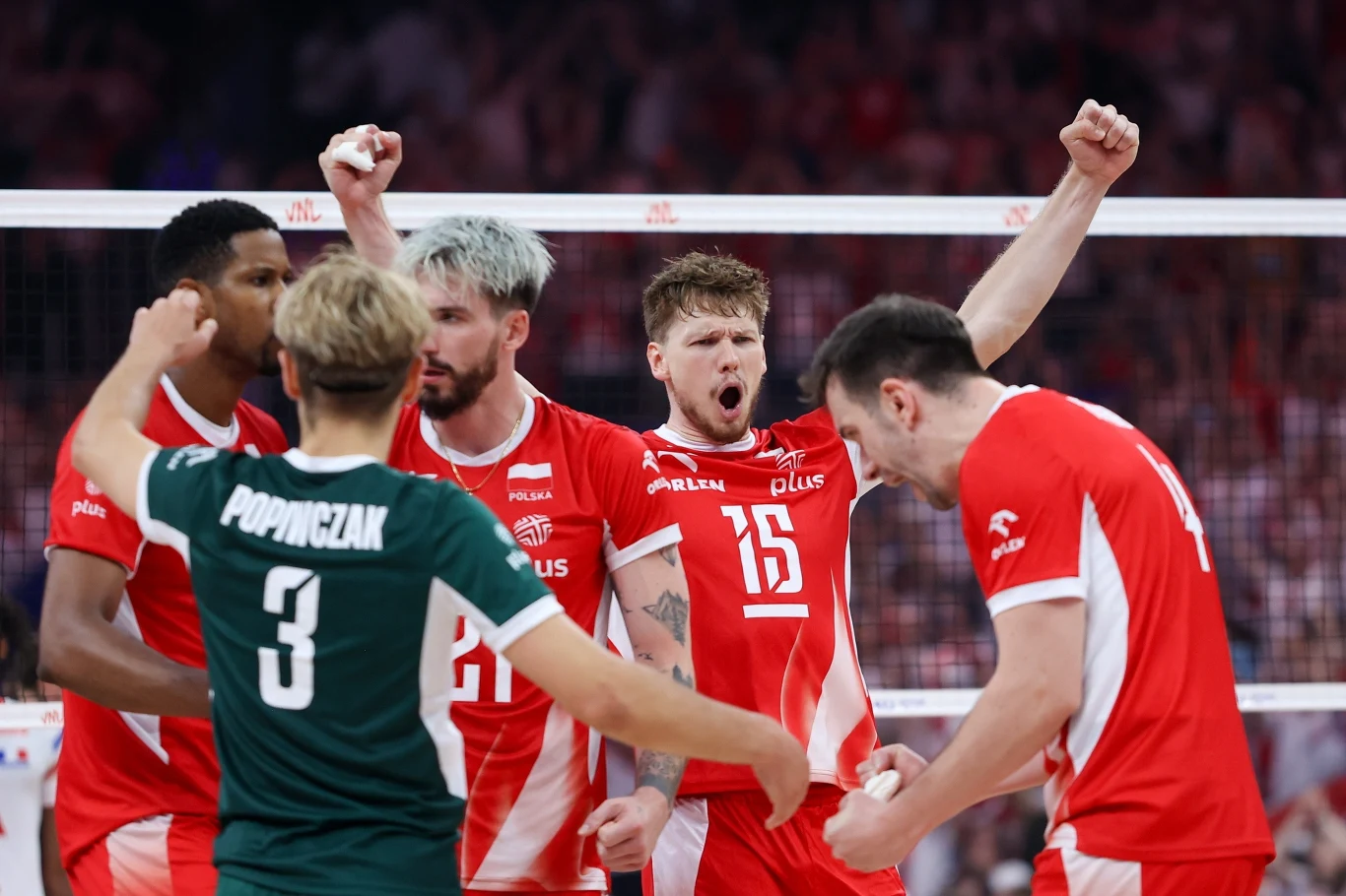 Zawodnicy polskiej reprezentacji siatkówki świętują zdobycie punktu podczas meczu, ubrani w charakterystyczne biało-czerwone stroje, z widoczną radością i podniesionymi rękami, na pierwszym planie wyróżnia się zawodnik z numerem 15.