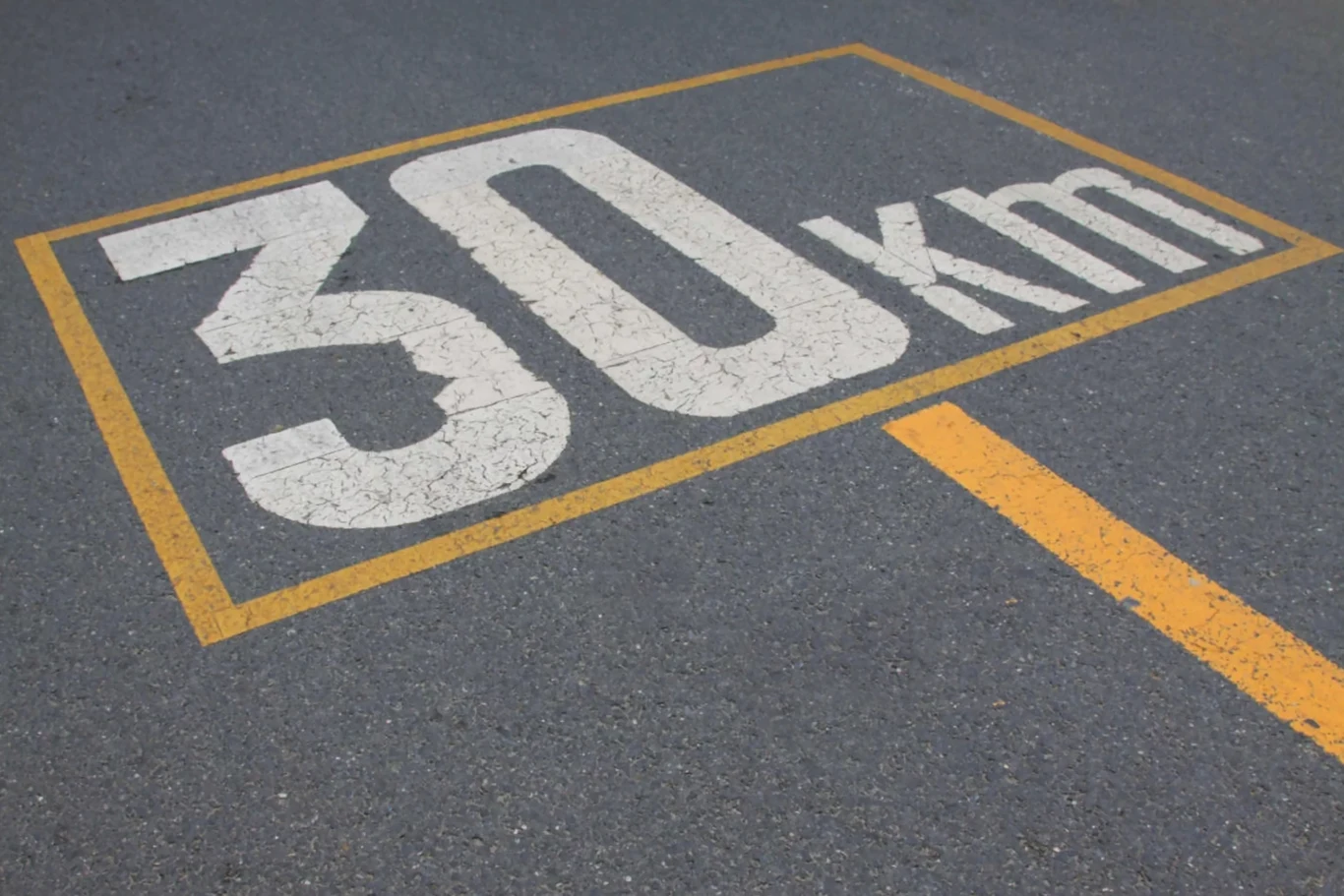 30 km/h w mieście i zero wypadków. Helsinki ogłosiły sukces Biały napis 30 km/h umieszczony na asfalcie, otoczony żółtym prostokątem, z żółtą linią oddzielającą na ulicy.