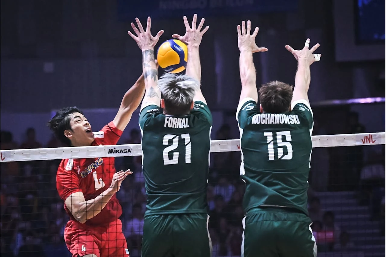 Jakub Kochanowski i Tomasz Fornal w bloku Dwóch siatkarzy w zielonych strojach próbuje zablokować atakującego zawodnika drużyny przeciwnej uderzającego piłkę po drugiej stronie siatki podczas intensywnej akcji meczowej.