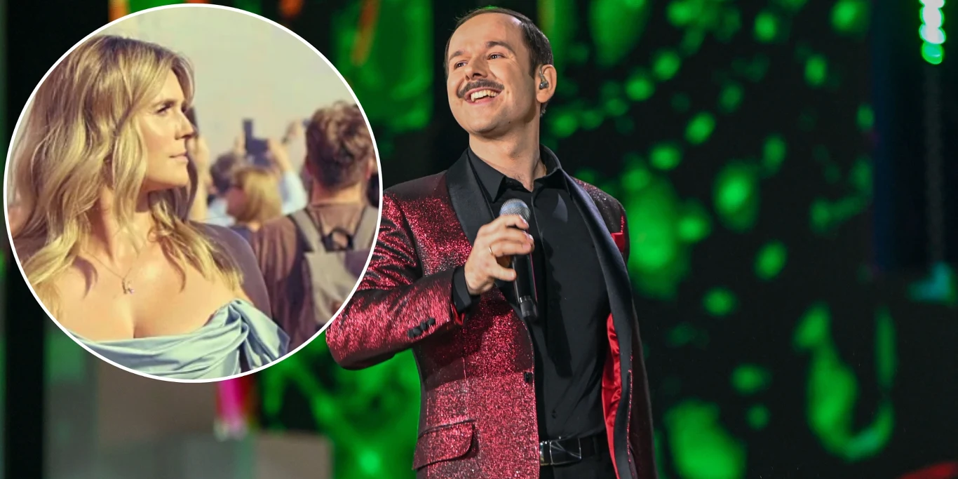 Sławomir z wyjątkowym teledyskiem i przesłaniem o Warszawie Mężczyzna w czerwonej, błyszczącej marynarce śpiewa na scenie z mikrofonem w ręku, tło sceniczne w odcieniach zieleni, w lewym górnym rogu zdjęcie kobiety w błękitnej sukni wśród kilku osób na świeżym powietrzu.