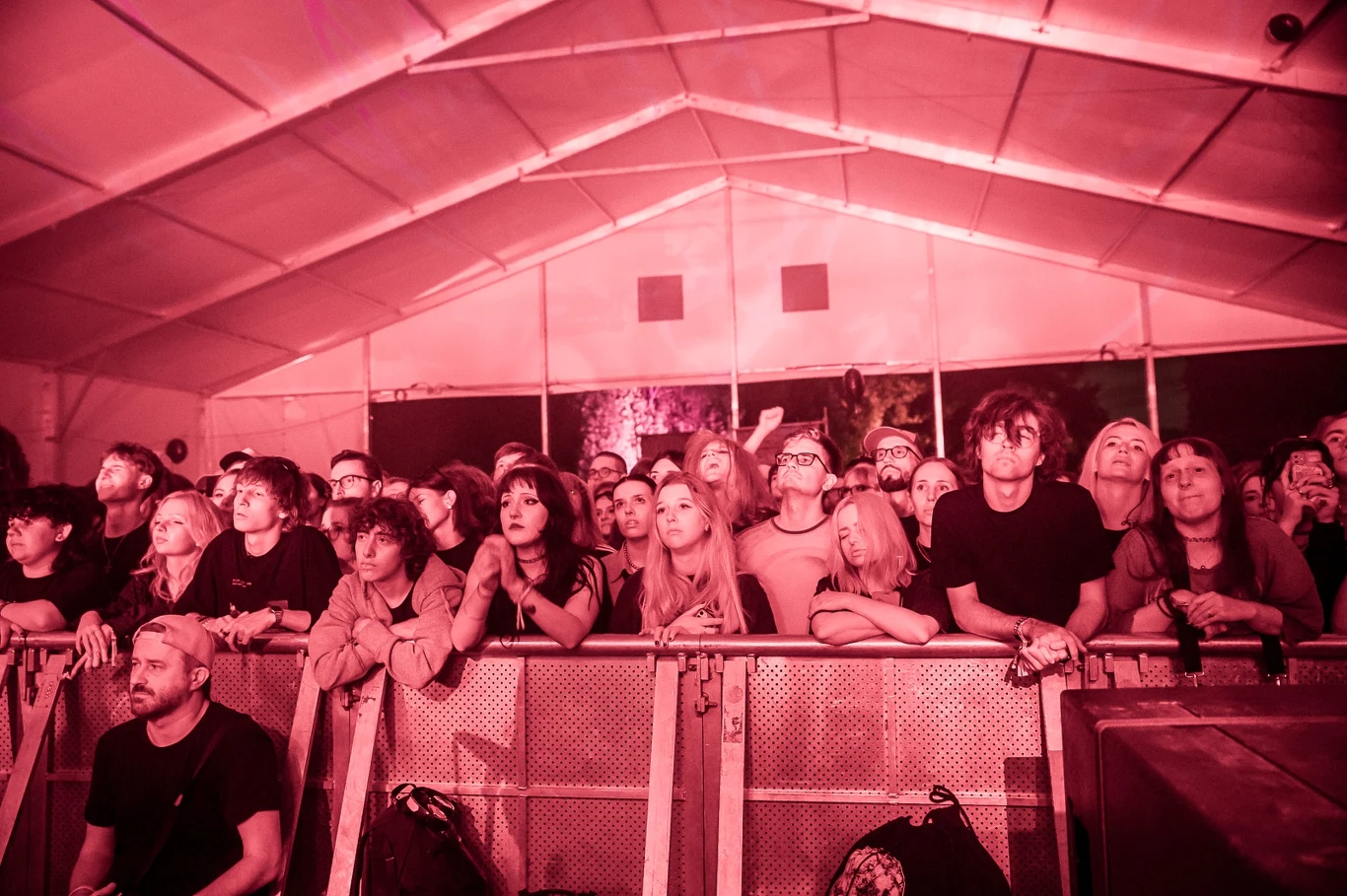 Publiczność OFF Festivalu Tłum ludzi stojących za barierkami podczas koncertu w zadaszonym miejscu, oświetlony czerwonym światłem, widoczne skupienie i emocje na twarzach uczestników.