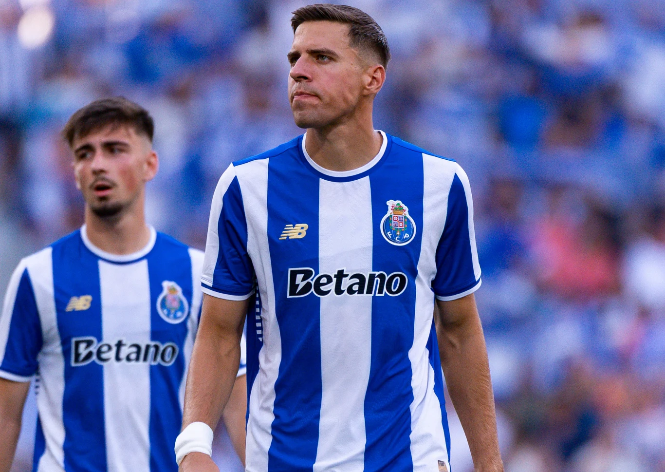 Dwóch piłkarzy FC Porto w oficjalnych koszulkach meczowych podczas rozgrywki na stadionie, w tle rozmyta publiczność.
