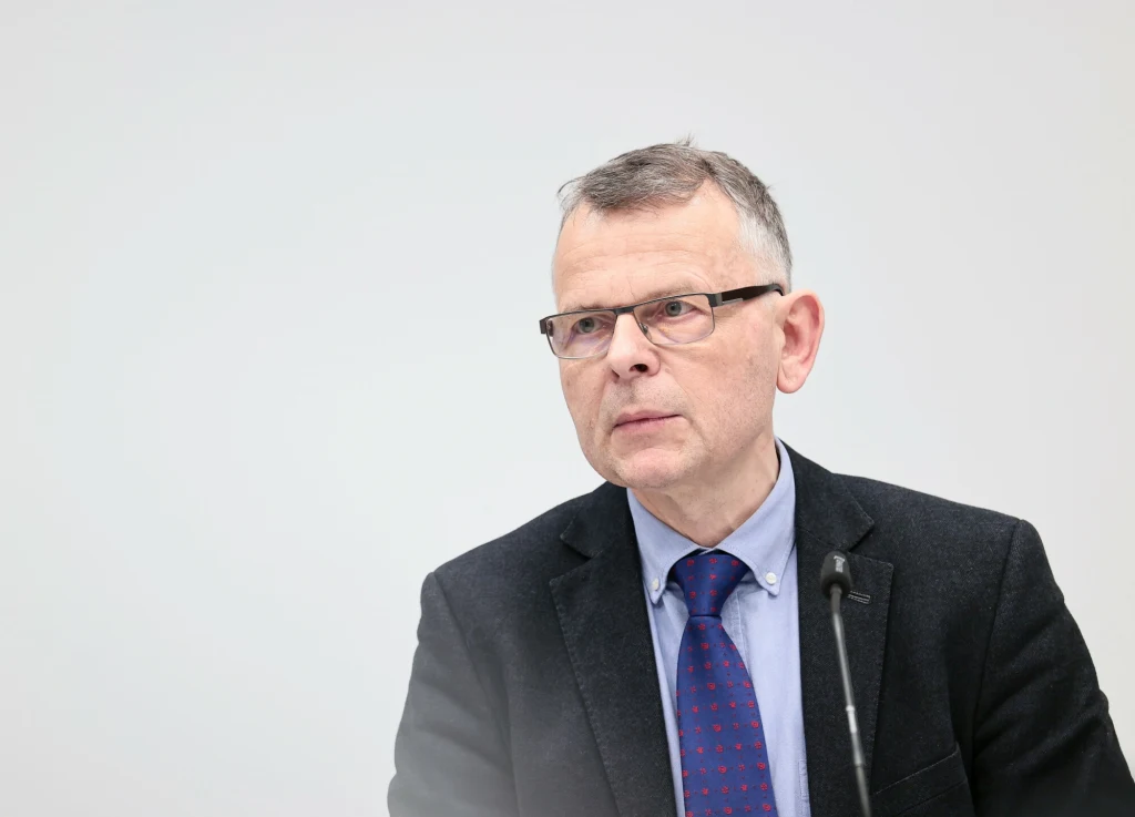 Stanowisko zajmowane przez Krzysztofa Ruchniewicza zostało zlikwidowane Mężczyzna w średnim wieku noszący okulary i elegancki garnitur, siedzący przed mikrofonem na tle jasnego minimalistycznego tła, wygląda skupiony i profesjonalny