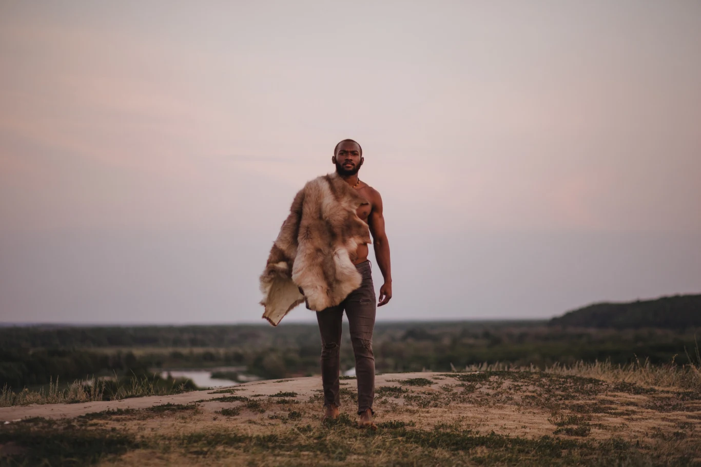 Homo sapiens mógł wygrać rywalizację z neandertalczykami przez... ołów Mężczyzna stojący na otwartym terenie, ubrany w spodnie i owinięty dużą futrzaną skórą zwierzęcia, z rozległym krajobrazem przyrody w tle