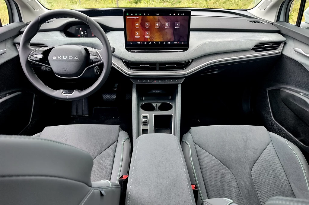 Szare wnętrze to jeden z nowych pakietów wykończenia o nazwie Design Selection Lounge Nowoczesna deska rozdzielcza samochodu Skoda z dużym wyświetlaczem multimedialnym na środku, minimalistyczne wnętrze z dwoma fotelami przednimi i kierownicą z logo marki.