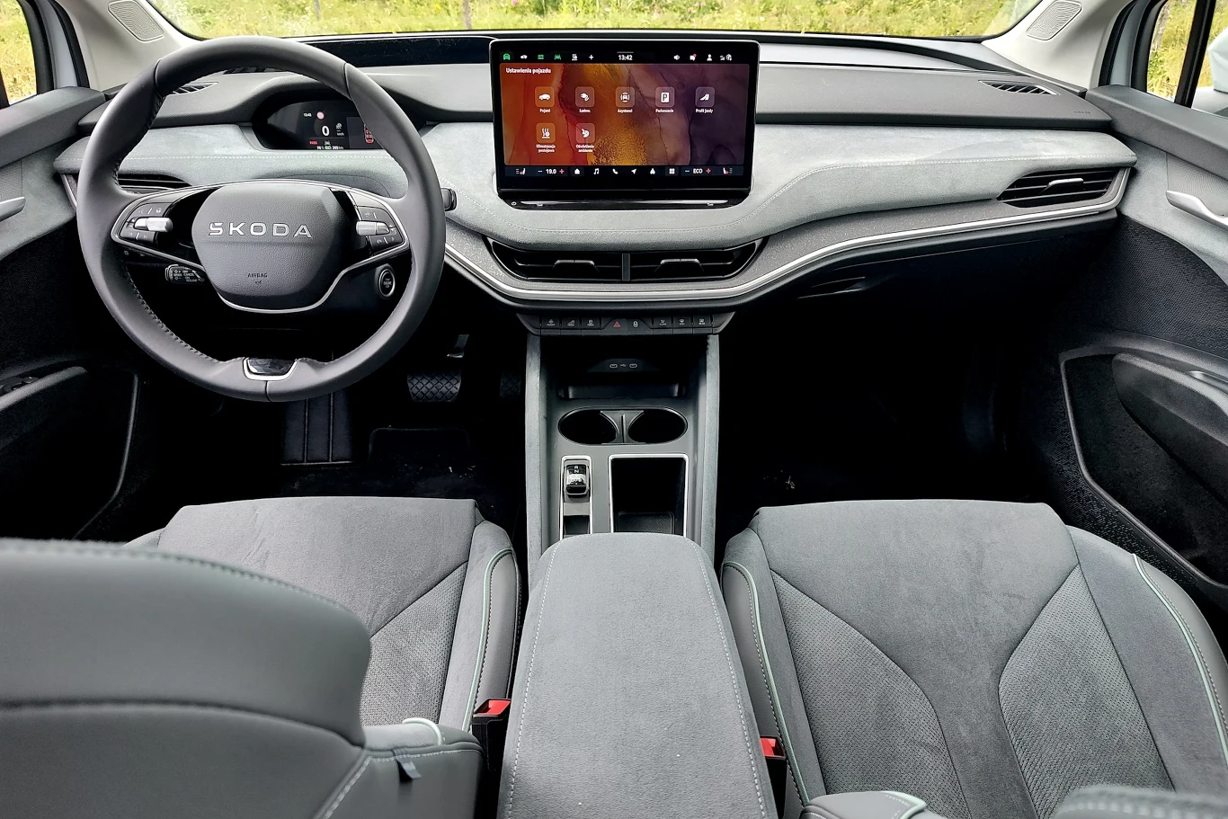 Nowoczesna deska rozdzielcza samochodu Skoda z dużym wyświetlaczem multimedialnym na środku, minimalistyczne wnętrze z dwoma fotelami przednimi i kierownicą z logo marki.