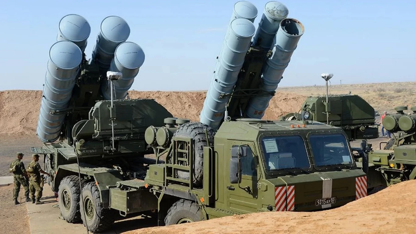 Eksplozja rosyjskiego systemu obrony S-400 Rakietowy system obrony powietrznej zamontowany na wojskowych pojazdach ciężarowych w pustynnym terenie, w tle kilku żołnierzy wykonujących czynności przy sprzęcie.