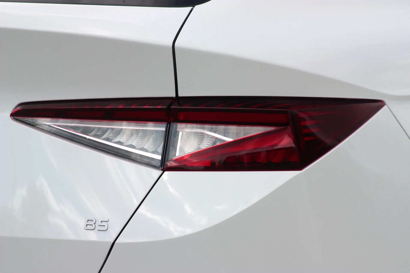 Tylne światło LED oraz fragment białej karoserii samochodu z oznaczeniem modelu 85.