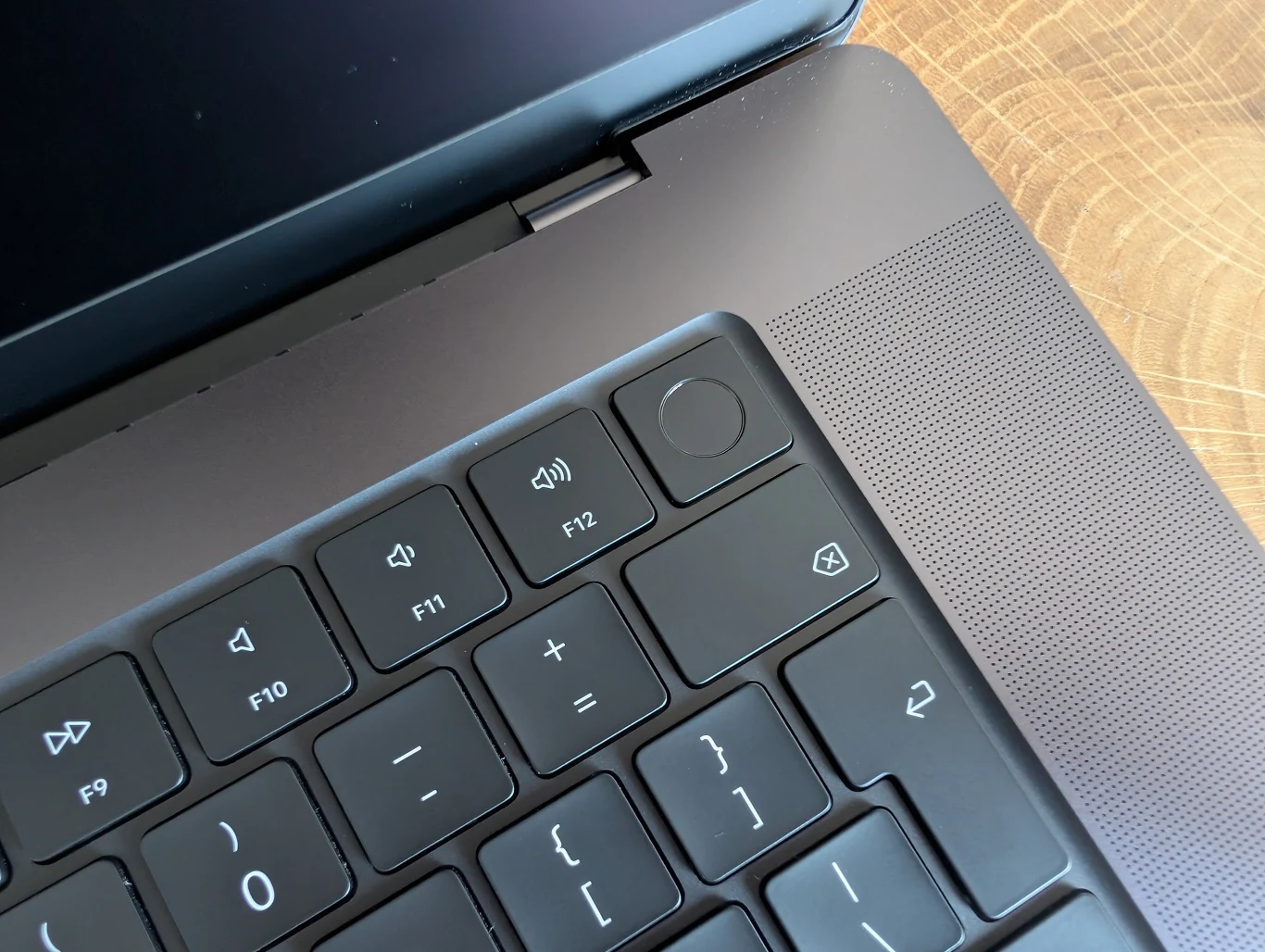 MacBook Pro 16" z M4 Pro Czarna klawiatura laptopa z wyraźnie widocznymi klawiszami funkcyjnymi, przyciskami regulacji dźwięku oraz przyciskiem zasilania w górnym prawym rogu. Po prawej stronie widoczne otwory na głośnik.
