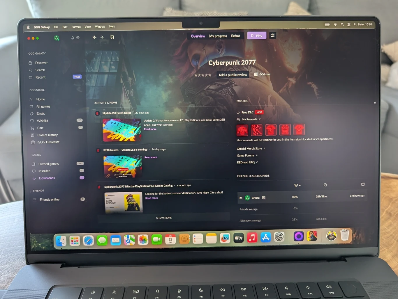 MacBook Pro 16" z M4 Pro Ekran laptopa prezentujący aplikację GOG Galaxy z wyświetloną biblioteką gier, na pierwszym planie widoczne są szczegóły dotyczące gry Cyberpunk 2077; na pasku zadań widoczne są ikony popularnych aplikacji systemu macOS