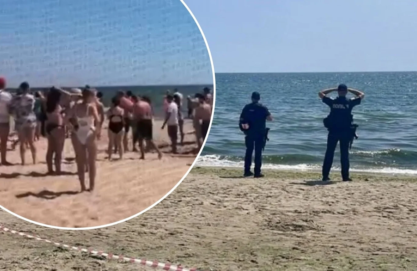 Na plaży w pobliżu Odessy w wyniku eksplozji zginęły trzy osoby Dwóch policjantów stoi na plaży obserwując morze, kilka metrów dalej znajduje się grupa ludzi zebranych na piasku, większość w strojach kąpielowych, pogoda jest słoneczna, niebo bezchmurne, widać wydzielony fragment plaży taśmą.