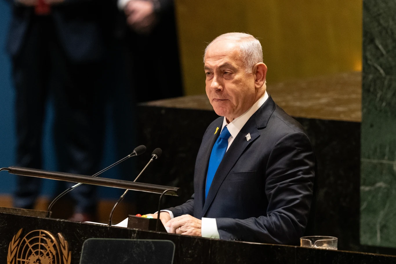 Binjamin Netanjahu zadeklarował, że "muszą dokończyć zadanie i pokonać Hamas" Mężczyzna w garniturze i niebieskim krawacie przemawia przy mównicy z logo ONZ na tle złotej ściany, odbywa się oficjalne wystąpienie podczas sesji w siedzibie Organizacji Narodów Zjednoczonych.