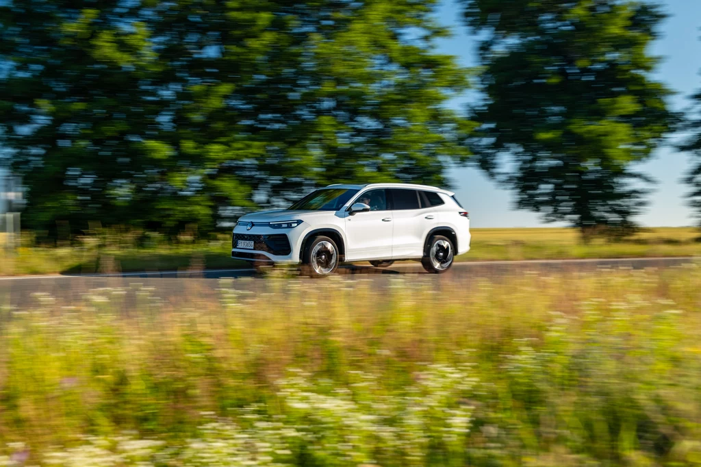 Dwulitrowy diesel o mocy 193 KM zachwyca kulturą pracy, niskim zużyciem paliwa i dynamiką, która nie wymaga od kierowcy wkręcania jednostki na wysokie obroty. Biały samochód typu SUV jedzie asfaltową drogą przez wiejską okolicę, wśród zieleni i wysokiej trawy, w tle porośnięte drzewami pola oraz błękitne niebo.