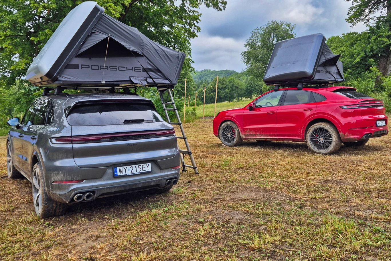 Namiot dachowy Porsche nawet po rozłożeniu wydaje się być niezbyt duży, ale zmieszczą się w nim nawet bardzo wysokie osoby Dwa samochody marki Porsche z zamontowanymi na dachach namiotami w terenie zielonym, jeden pojazd srebrny, drugi czerwony, oba stoją na trawie w otoczeniu drzew i mają rozłożone schodki prowadzące do namiotów.