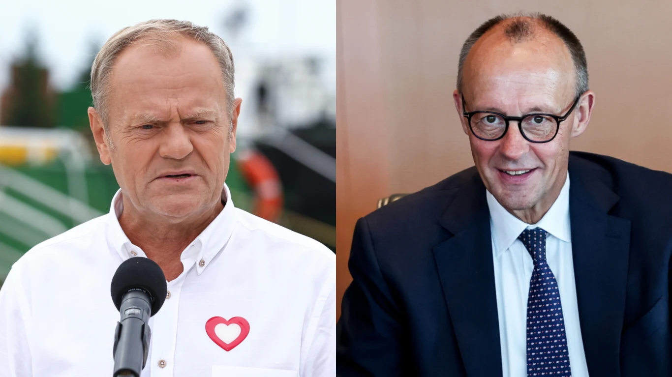 Kanclerze Niemiec Friedrich Merz i premier Donald Tusk Dwóch mężczyzn, jeden w białej koszuli z przypiętym znaczkiem w kształcie serca przemawia do mikrofonu na tle zewnętrznym, drugi w garniturze i okularach siedzi w pomieszczeniu przy stole i się uśmiecha.