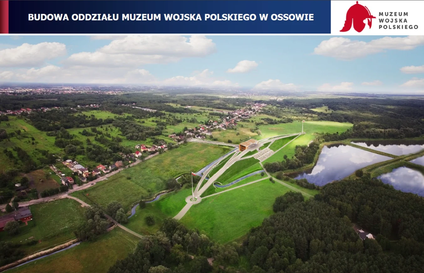 Muzeum Bitwy Warszawskiej Widok z lotu ptaka na teren budowy oddziału Muzeum Wojska Polskiego w Ossowie, z widocznymi przebiegającymi alejkami, nowoczesną zabudową w centrum oraz otaczającą zielenią, zbiornikiem wodnym i pobliską zabudową mieszkalną.