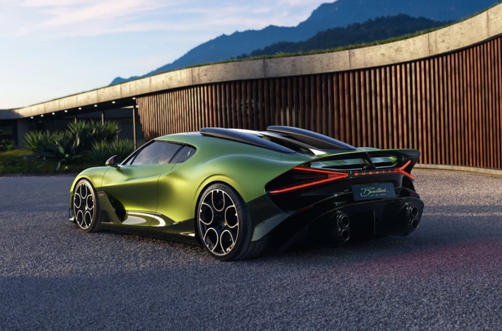 Detale Bugatti Brouillard robią wrażenie nawet na najbardziej wymagających. Zielony supersamochód sportowy o niskiej sylwetce stoi na utwardzonym podłożu, w tle nowoczesny budynek z drewnianą elewacją oraz góry pod jasnym, wieczornym niebem.