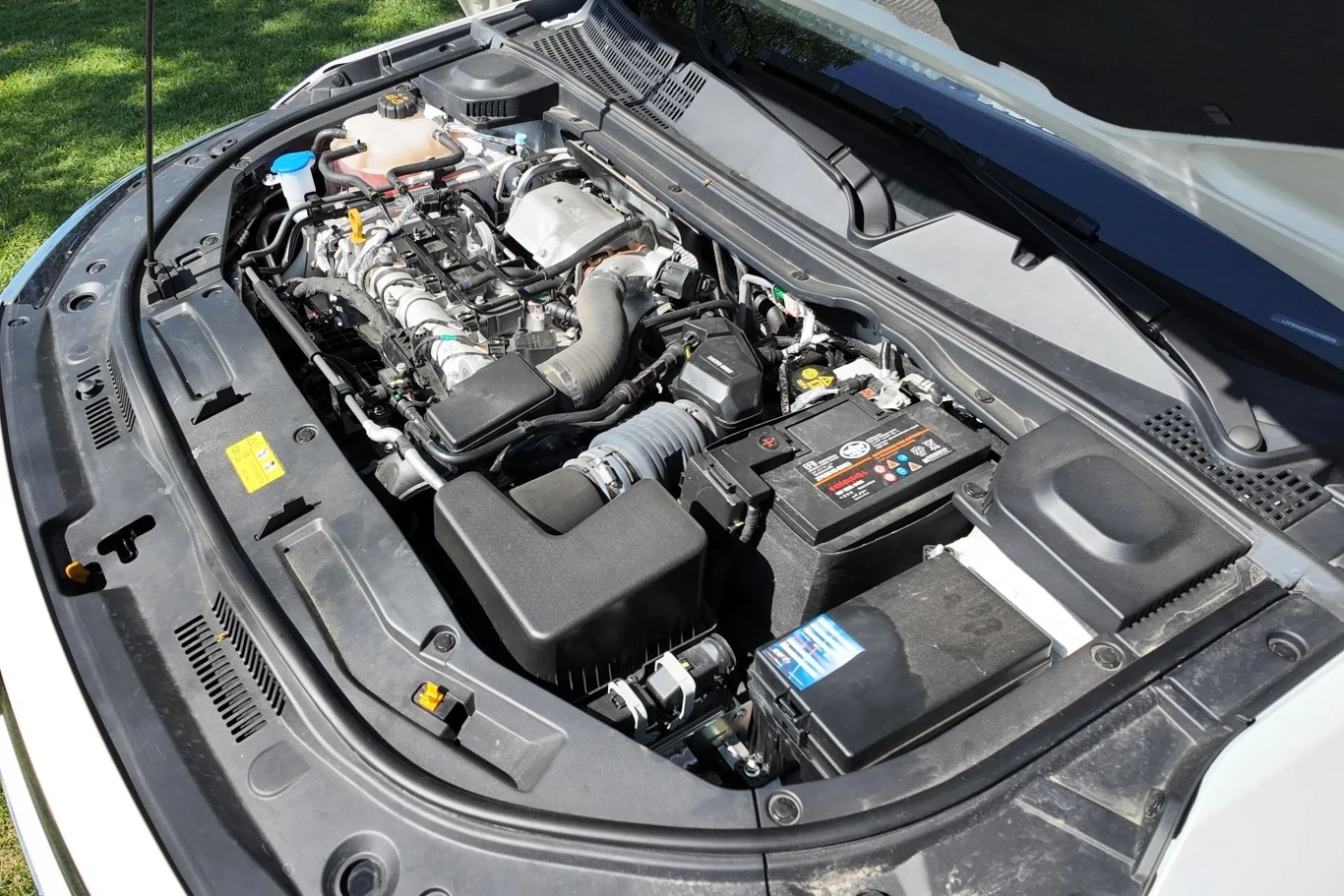 Komora silnika samochodowego z widocznym akumulatorem, przewodami, filtrem powietrza oraz innymi elementami mechaniki pojazdu, całość w dobrym stanie technicznym.