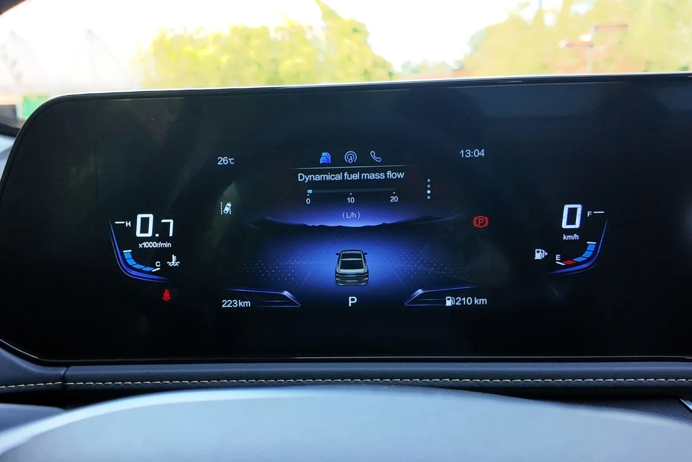 Cyfrowy wyświetlacz deski rozdzielczej auta pokazuje parametry jazdy, takie jak prędkość, ilość paliwa, temperatura oraz stan techniczny pojazdu, z wizualizacją auta w centrum ekranu.