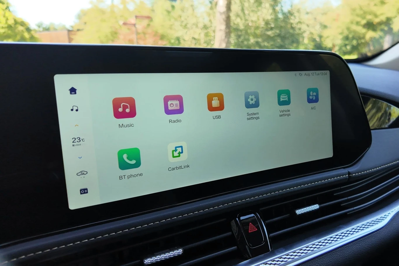 Nowoczesny ekran dotykowy systemu multimedialnego w samochodzie prezentujący kolorowe ikony różnych funkcji, takich jak muzyka, radio, ustawienia systemu, telefon i klimatyzacja, z czytelnym interfejsem użytkownika.