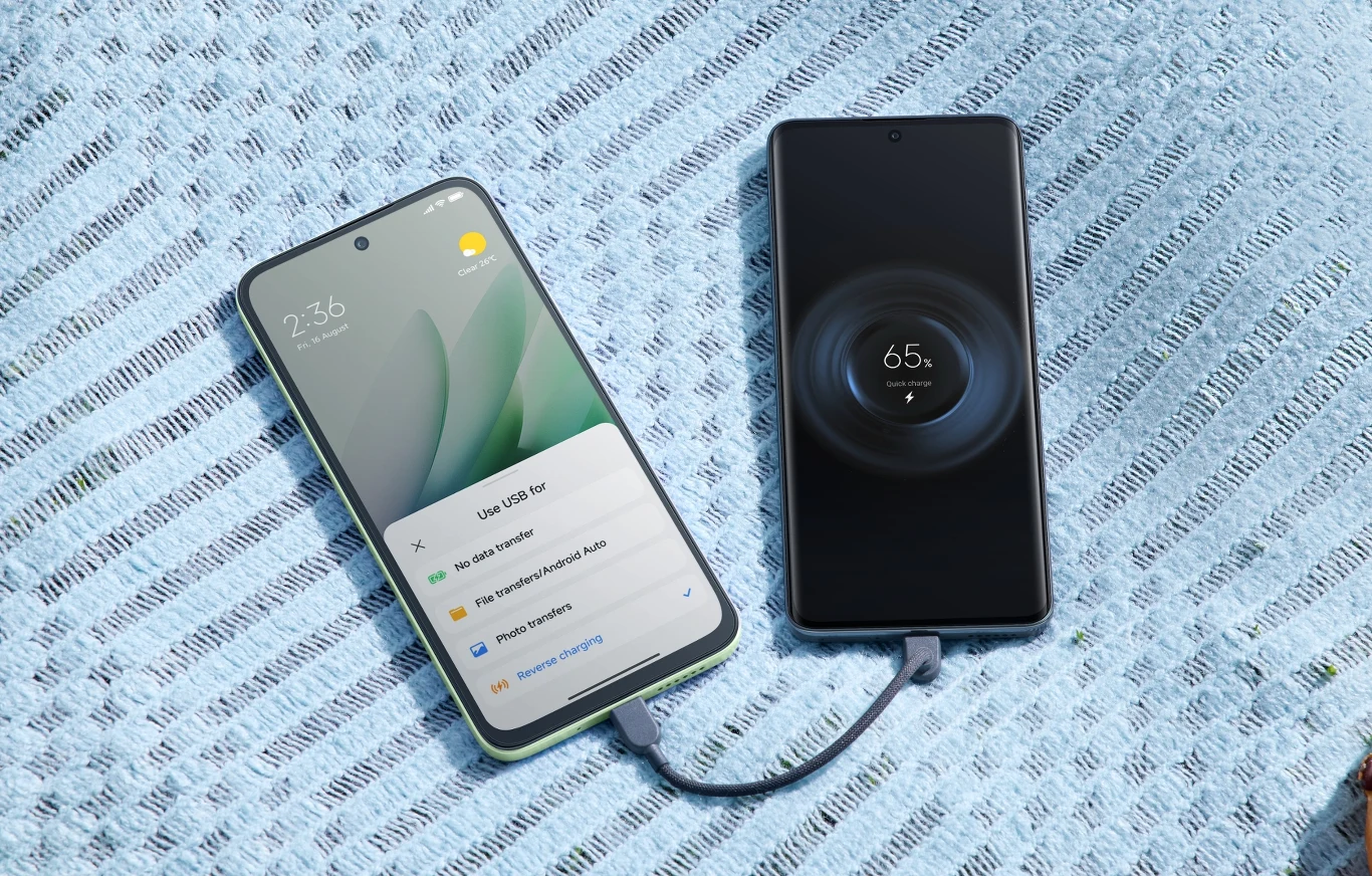 Redmi 15 5G oraz 4G debiutują w Polsce. Znamy ceny i specyfikacje. Dwa nowoczesne smartfony leżą na niebieskiej powierzchni, połączone krótkim kablem USB; jeden z nich ładuje drugi, co widać po wyświetlanym wskaźniku ładowania 65% na ekranie.