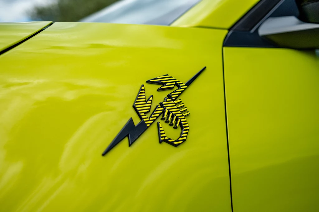 Abartha 600e ozdobiono całym mnóstwem emblematów ze skorpionem. Na przednich błotnikach połączono go z błyskawicą, podkreślając, iż jest to Abarth elektryczny Jaskrawożółty błotnik samochodu z widocznym czarno-żółtym oznaczeniem w kształcie błyskawicy i stylizowaną liczbą 35.