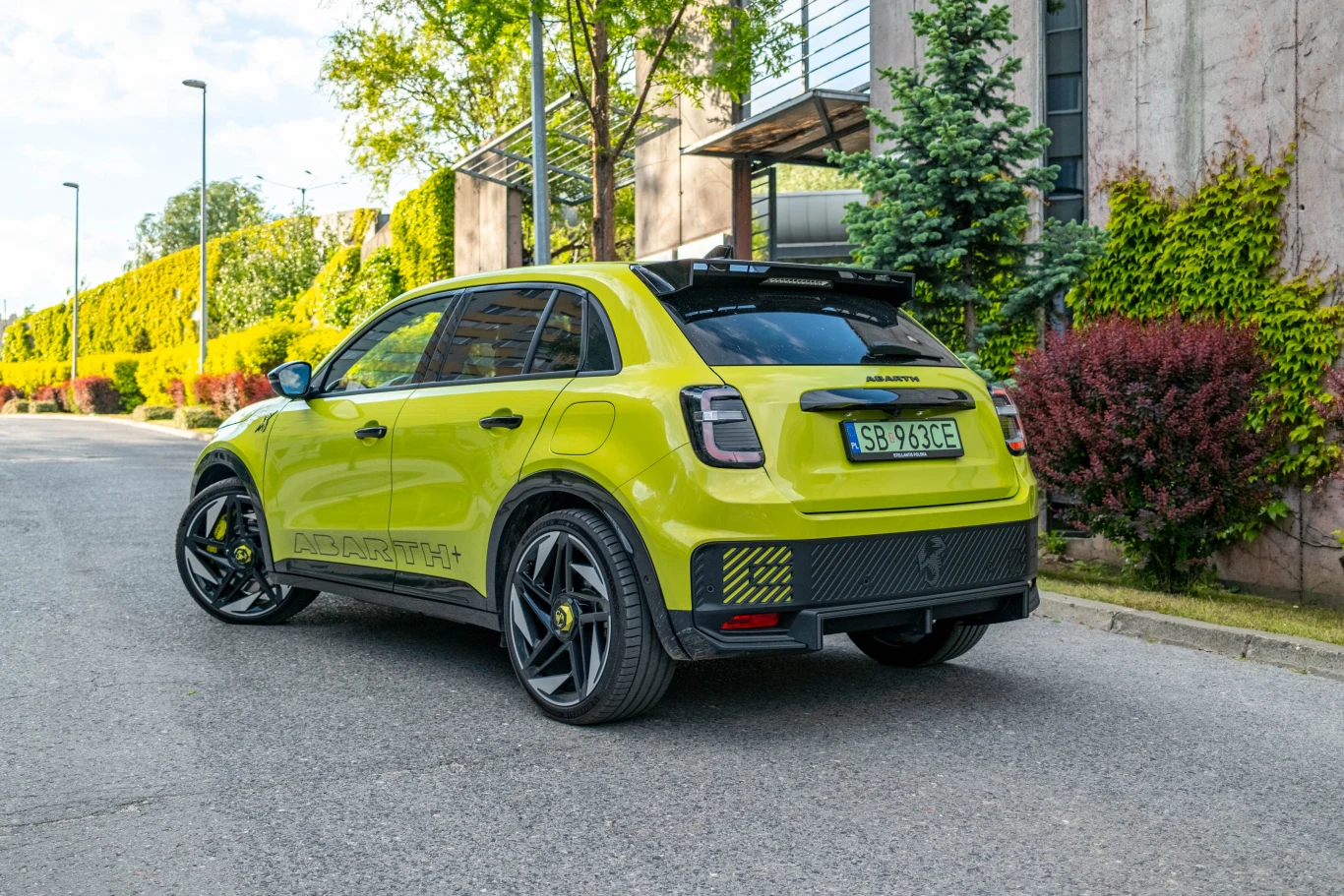 Jaskrawozielony samochód osobowy marki Abarth zaparkowany na ulicy w otoczeniu roślin i budynków mieszkalnych, z widocznym sportowym charakterem oraz dynamicznymi liniami nadwozia.
