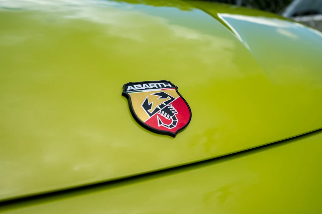 Abarth 600e Scorpionissima Logo marki Abarth umieszczone centralnie na jasnozielonej masce samochodu.