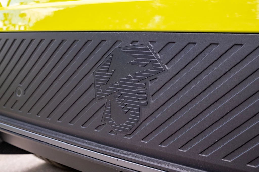 Abarth 600e Scorpionissima Czarna listwa ochronna z tłoczonym wzorem geometrycznym oraz żółtym fragmentem karoserii samochodu.