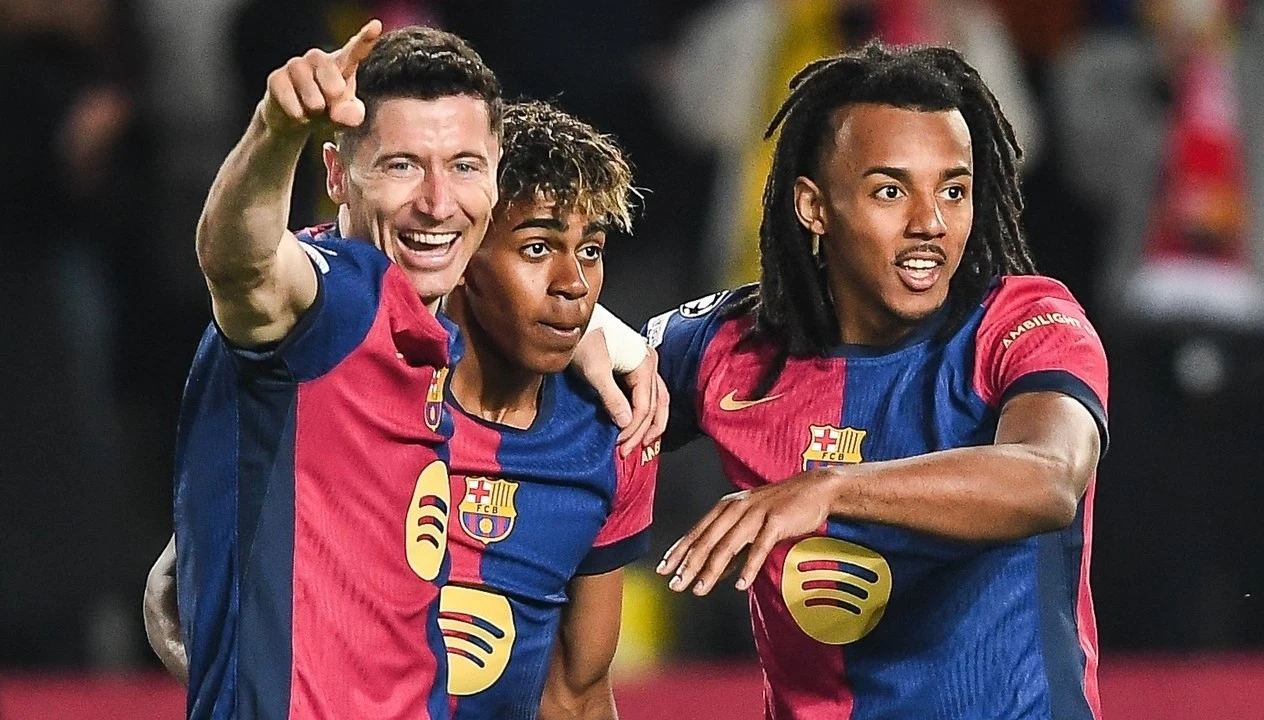 Jules Kounde (pierwszy z prawej) ustalił z Barceloną warunki kontraktu do 2030 roku Trzech piłkarzy FC Barcelony w koszulkach klubowych świętuje zdobycie bramki, jeden z zawodników pokazuje coś ręką w kierunku trybun, wszyscy mają wyraz radości na twarzy, na dalszym planie widoczny jest rozmyty tłum kibiców.