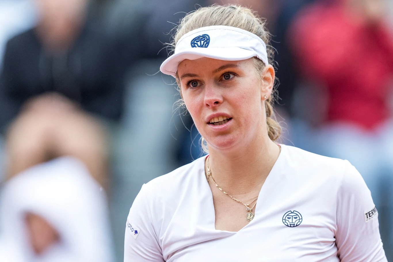 Magdalena Fręch wycofała się z turnieju WTA 500 w Monterrey Kobieta w białym stroju sportowym i białej czapce z daszkiem na tle rozmytego tłumu, z lekkim wyrazem skupienia na twarzy.