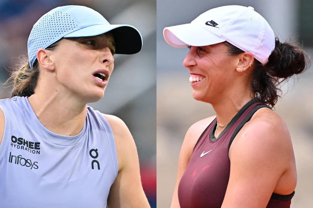 Dwie kobiety w sportowych czapkach i strojach tenisowych podczas rozmowy lub wymiany zdań, tło rozmyte.