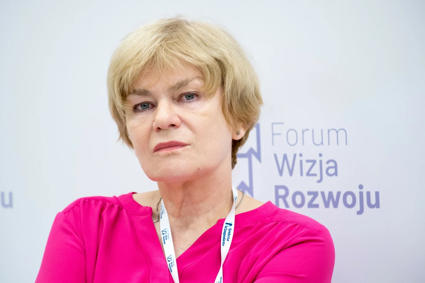 Dorota Kania z zarzutami. Prokuratura kieruje akt oskarżenia do sądu Kobieta o jasnych włosach, ubrana w różową bluzkę, spogląda w stronę obiektywu, w tle widoczne logo wydarzenia Forum Wizja Rozwoju.
