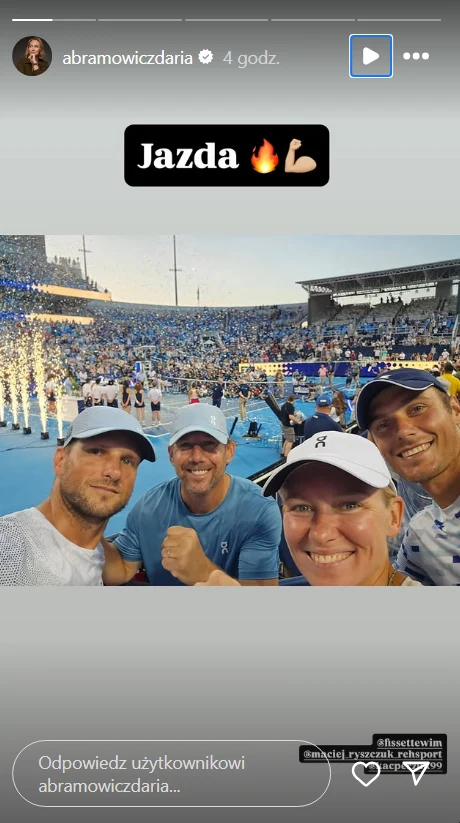Maciej Ryszczuk, Wim Fissette, Daria Abramowicz i Jules Mercier świętują zwycięstwo Igi Świątek Czwórka ludzi w sportowych ubraniach uśmiecha się, robiąc selfie na tle dużego stadionu wypełnionego widownią, w pobliżu efektowne fajerwerki świetlne podkreślające atmosferę sportowego wydarzenia.