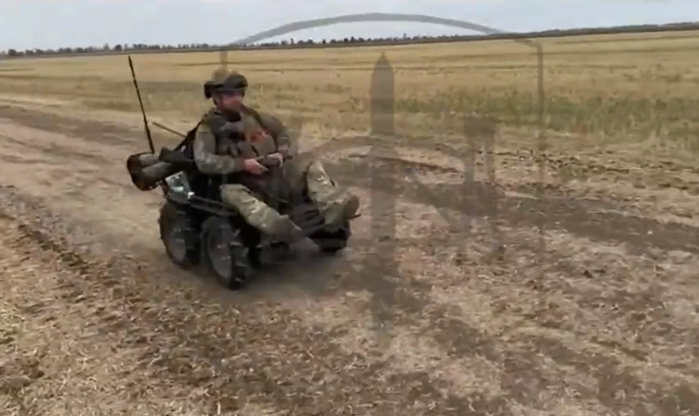 Termit w wersji szturmowej może dostarczyć na front jednego żołnierza wraz z kilkoma skrzynkami amunicji, wody i racji żywnościowych Żołnierz w mundurze wojskowym porusza się po polu na zdalnie sterowanej maszynie przypominającej wózek terenowy, otoczenie to płaski teren uprawny, sucha ziemia i szerokie puste pole