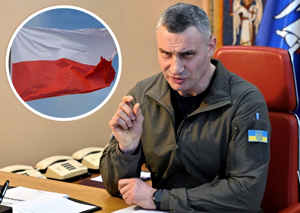 Mer Kijowa Witalij Kliczko Mężczyzna w wojskowej kurtce z naszywką ukraińskiej flagi siedzi przy biurku, wykonując gest ręką, na tle biura z widocznymi telefonami i religijną ikoną; w okrągłej ramce w lewym górnym rogu znajduje się zdjęcie polskiej flagi.