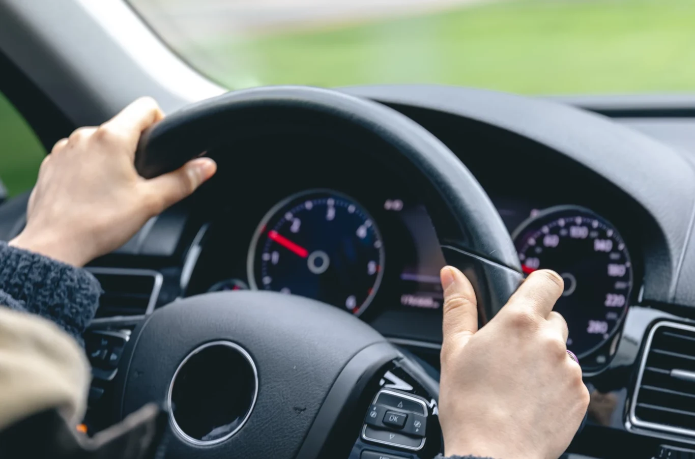 Na czym polega regeneracja turbosprężarki? Ręce trzymające kierownicę samochodu, dobrze widoczne wnętrze kokpitu z wyraźnymi wskaźnikami na desce rozdzielczej.