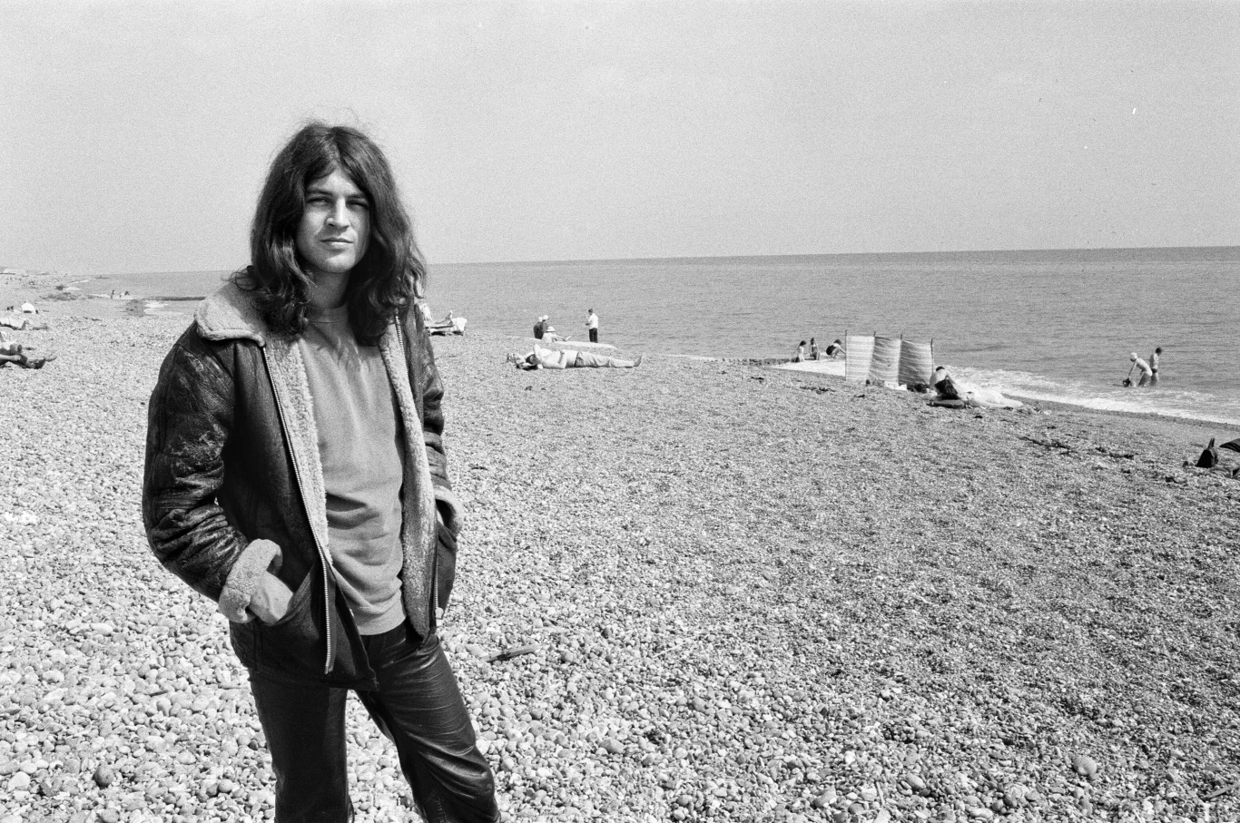 Ian Gillan w 1970 r. wcielił się w rolę Jezusa w rock operze "Jesus Christ Superstar" Młody mężczyzna z długimi włosami stoi na kamienistej plaży nad morzem; w tle widoczne są pojedyncze osoby wypoczywające oraz kosze plażowe.