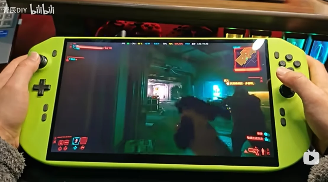 Duża konsola do gier przypominająca wyglądem Nintendo Switch trzymana w dłoniach, na ekranie widoczna dynamiczna scena z gry komputerowej z widokiem pierwszoosobowym, jasne przyciski i szczegóły obudowy konsoli.
