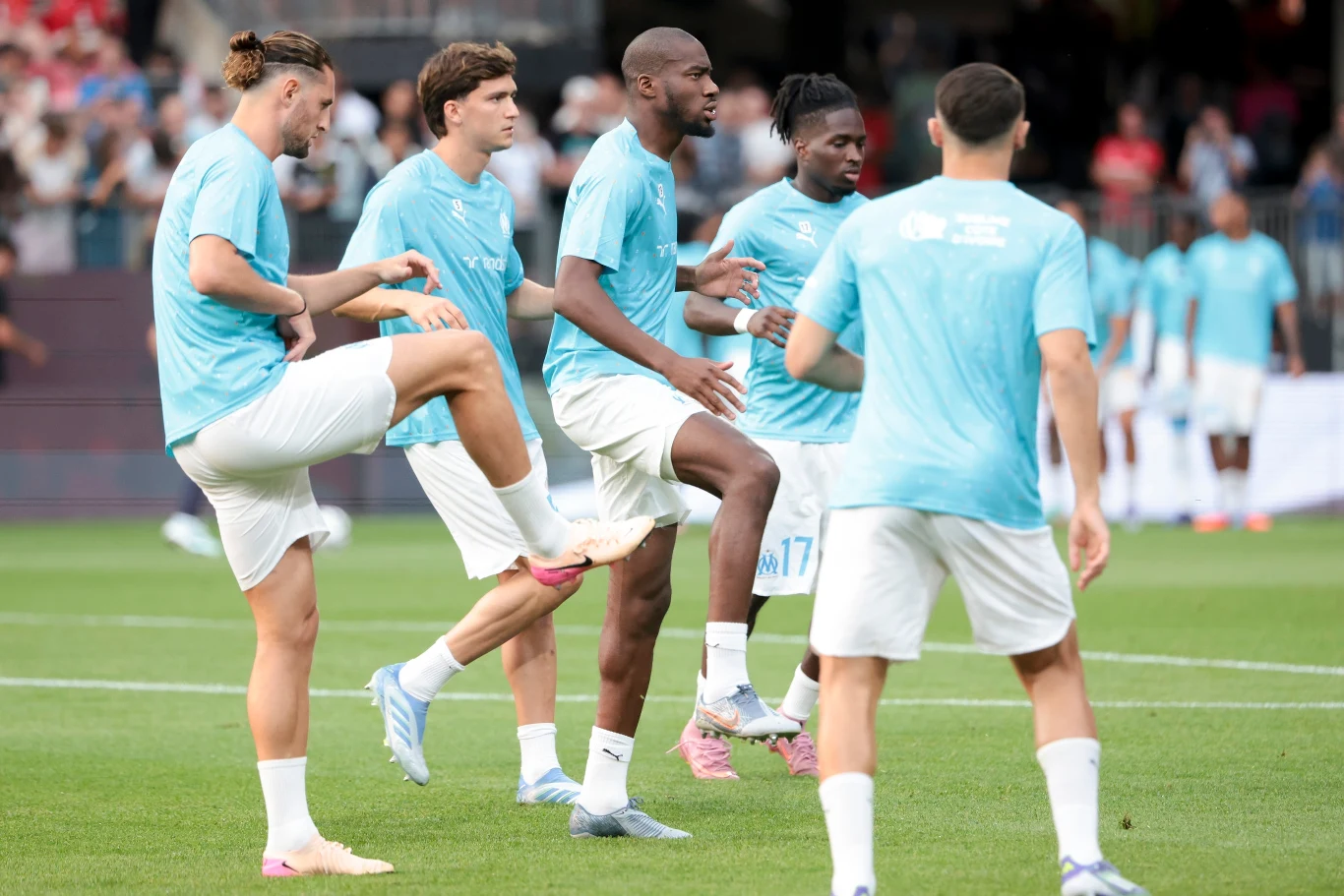 Adrien Rabiot (pierwszy z lewej) i Jonathan Rowe (czwarty z lewej) zostali de facto wyrzuceni z Olympique Marsylia Grupa piłkarzy w jasnoniebieskich koszulkach i białych spodenkach wykonuje rozgrzewkę na boisku, w tle widać widownię i trybuny stadionu.