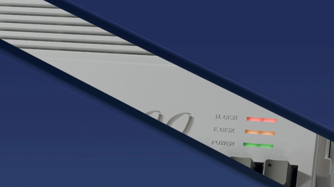 Tajemniczy sprzęt od Retro Games Limited Fragment obudowy retro komputera z widocznymi trzema wskaźnikami LED opisanymi jako H. Disk, F. Disk i Power, częściowo zakryty niebieskim elementem graficznym.