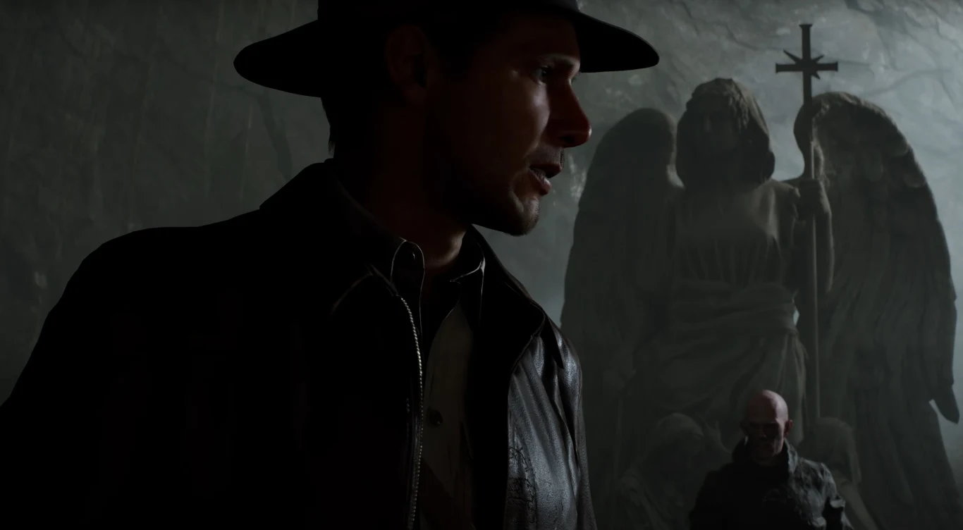Indiana Jones Mężczyzna w ciemnym kapeluszu i skórzanej kurtce stoi na pierwszym planie w słabo oświetlonym miejscu, w tle wyłania się kamienna rzeźba anioła z krzyżem, z tyłu widoczna jest jeszcze jedna, słabo oświetlona postać.