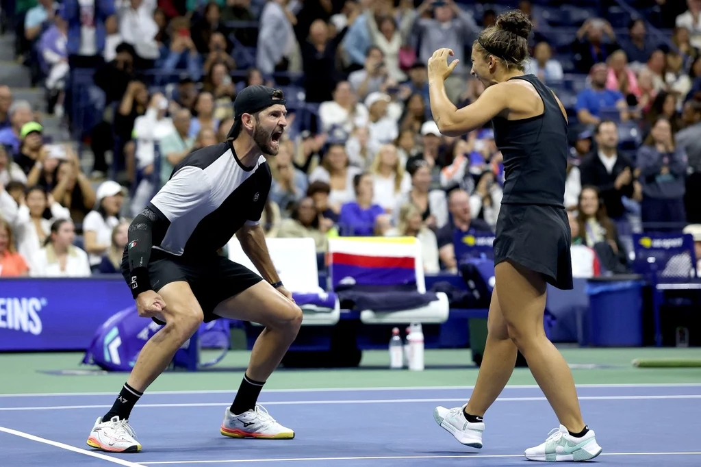 Sara Errani i Andrea Vavassori wygrali US Open Dwójka tenisistów świętuje wspólnie udany punkt na korcie, tłum kibiców w tle, sportowa atmosfera i emocje widoczne na twarzach zawodników.