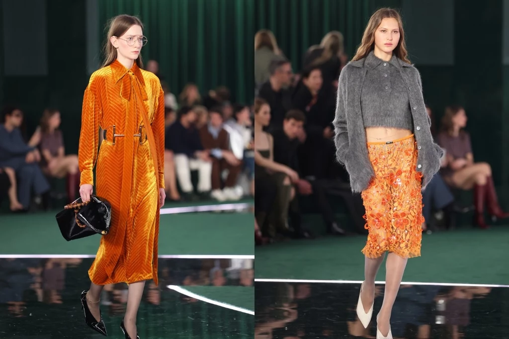 Gucci jesień/zima 2025-2026 Dwie modelki idą po wybiegu podczas pokazu mody, jedna ubrana w pomarańczową sukienkę z połyskiem i czarne dodatki, druga w szary sweter i pomarańczową cekinową spódnicę, w tle widzowie siedzący przy zielonej kurtynie.
