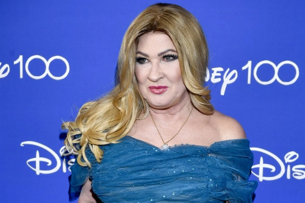 Beata Kozidrak powraca na scenę Kobieta w niebieskiej sukni z odkrytymi ramionami pozuje na tle niebieskiej ściany z białym napisem Disney 100.