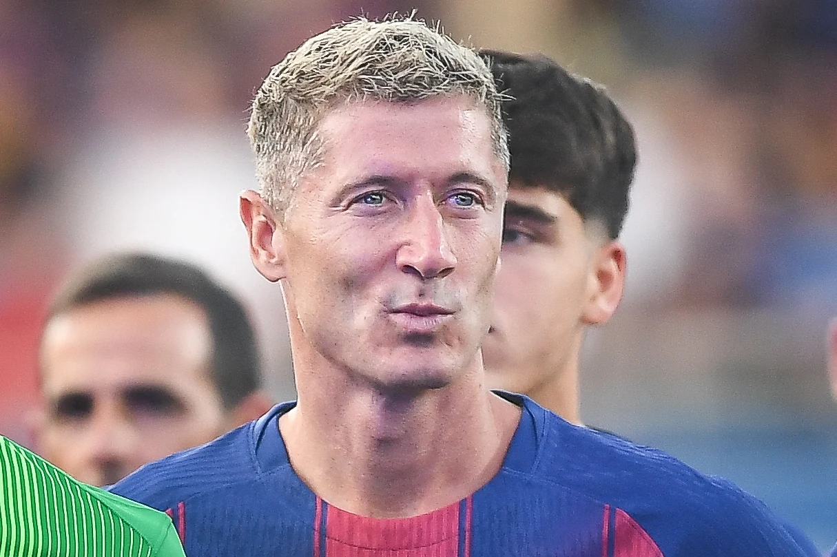 Robert Lewandowski Mężczyzna w sportowej koszulce w niebiesko-czerwone pasy stoi w tłumie innych osób, wyróżnia się jasnymi, krótkimi włosami i skupioną miną.