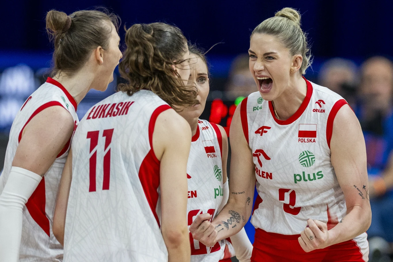 Zawodniczki polskiej reprezentacji siatkarskiej w białych i czerwonych strojach celebrują zdobycie punktu podczas meczu, okazywanie radości, determinacji i sportowej energii.