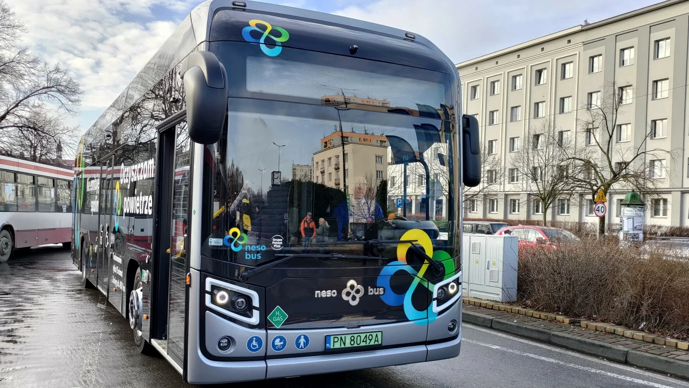 W Rzeszowie będzie jeździć 20 autobusów wodorowych Nowoczesny autobus elektryczny z oznaczeniami nesa bus stoi na ulicy w mieście, w tle widoczny budynek biurowy oraz bezlistne drzewa.
